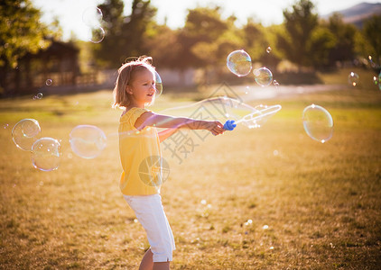 泡泡棒在公园里泡大泡泡的小女孩背景