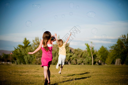 2个小女孩在公园里追逐泡泡图片