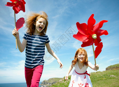 兴高采烈的两个女孩在红色风车旁欢笑背景