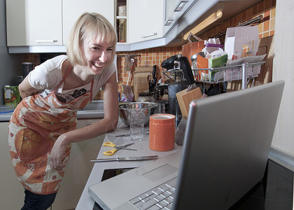 女人用笔记本电脑在厨房做饭图片