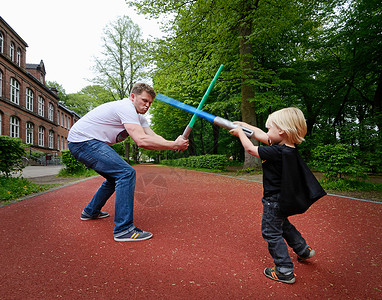 父子俩用玩具剑打架背景图片