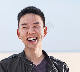 海滩上微笑的年轻人的肖像高清图片