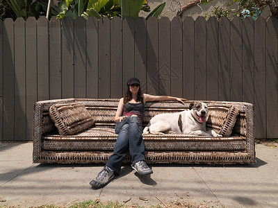 女人和狗在沙发上休息图片