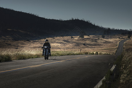 骑在公路上的中年男性摩托车手背景图片