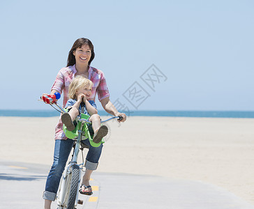美国加利福尼亚州威尼斯海滩上的妇女和儿子骑车图片