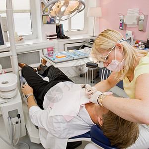 为男性患者工作的女性牙医图片