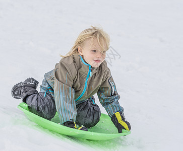 在雪中玩托博根的男孩图片