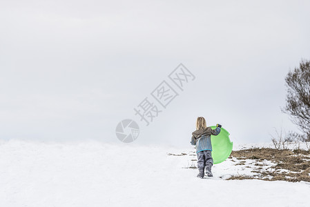 雪中抱着托博根的孩子的后视图图片