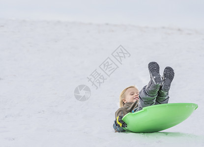 在雪中玩托博根的男孩高清图片