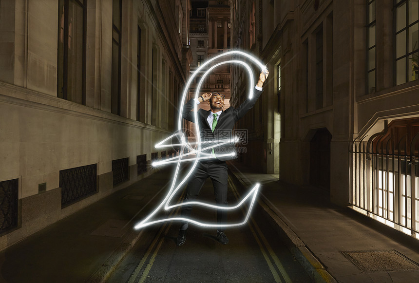 在英国伦敦的晚上，年轻的商人在城市街道上轻画英镑符号图片