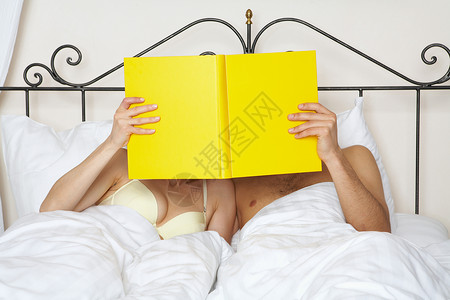 年轻夫妇抱着黄皮书躺在床上图片