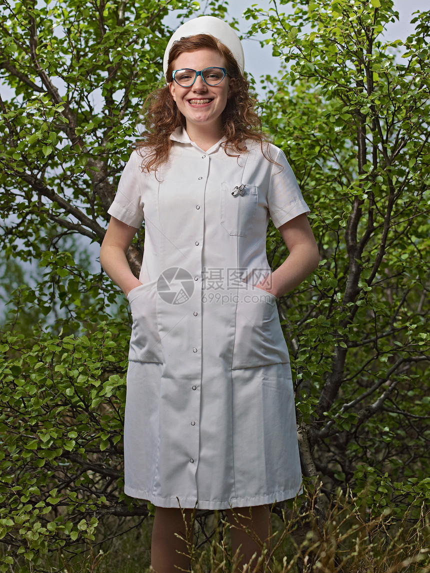 戴眼镜的护士站在灌木丛中图片