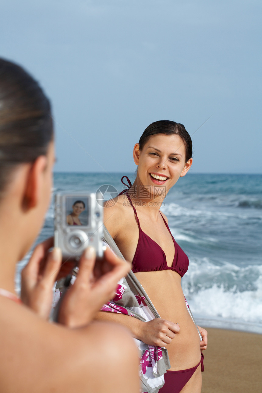 海滩上的两个年轻女人在拍照图片