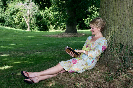 女人靠在树上看书图片
