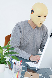 戴着撞车假面具的人在电脑前工作背景