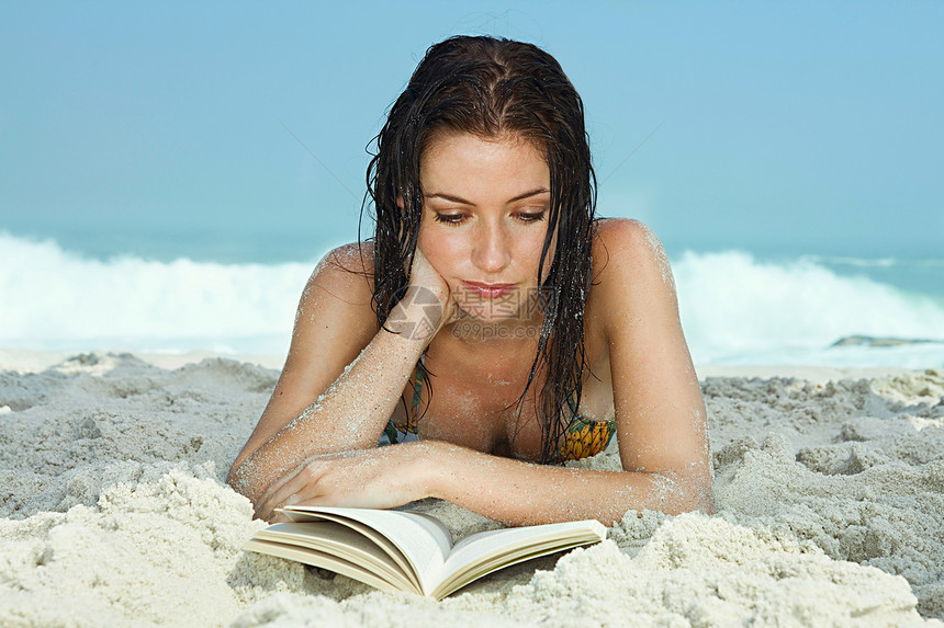 海滩上的年轻女人在看书图片