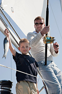小男孩与帆船父子在游艇上钓鱼背景