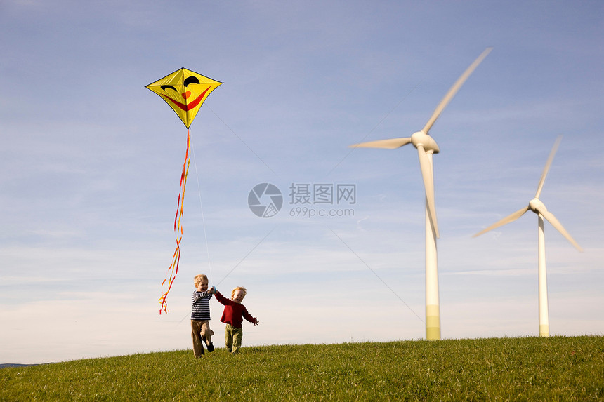 两个男孩在风力涡轮机上放风筝图片