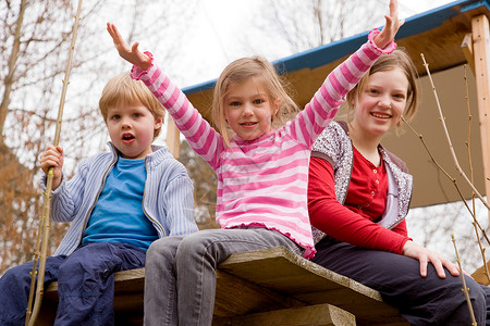 三个孩子坐在树屋里背景图片