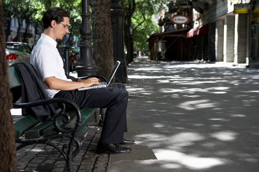 坐在长椅上用笔记本电脑工作的人图片