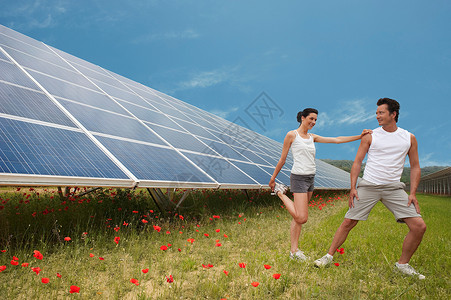 在太阳能板旁做运动的一对夫妇图片