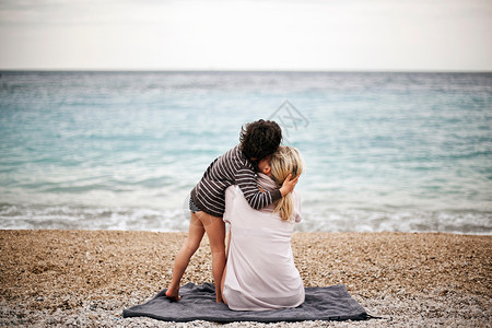 男孩抱着母亲在海滩上图片