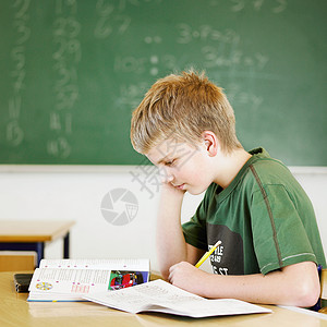 在教室书桌上学习的男孩写作高清图片素材
