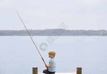 男孩在湖边钓鱼图片