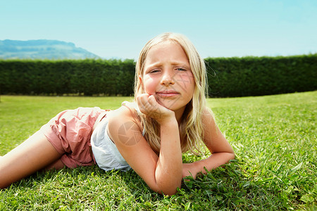 好奇的女孩躺在草地上背景图片