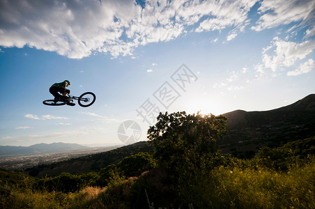 山地自行车手在山坡上跳跃背景图片