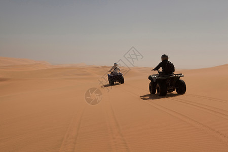 人们在沙地上驾驶四轮车图片