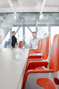 坐在会议室橙色椅子上的男人图片