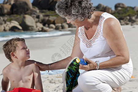 和孙子坐在海滩上的女人图片