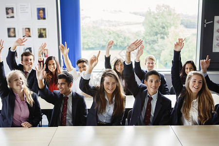 拿手机的外国人在教室里举起手的青少年学生背景