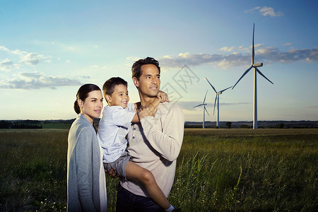 风力发电机背景前的一家三口肖像图片
