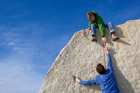 奋斗的男人攀岩者帮助同伴背景