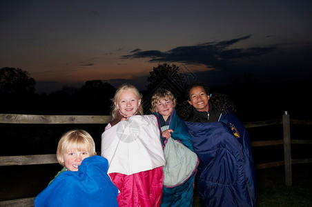 黄昏时孩子们穿着睡袋在外面背景图片