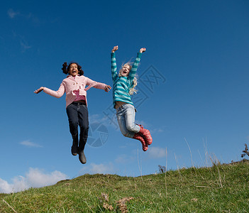 两个年轻女孩在山上跳跃背景图片