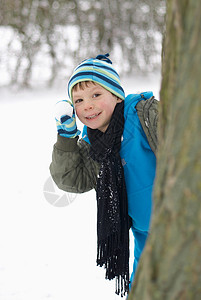 男孩背着雪球躲在树后图片