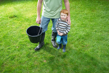 提着水桶的男孩父亲和儿子在后院提着水桶背景