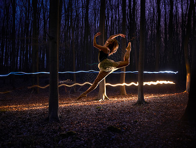 伸腿在黑暗的森林中跳的女舞者背景