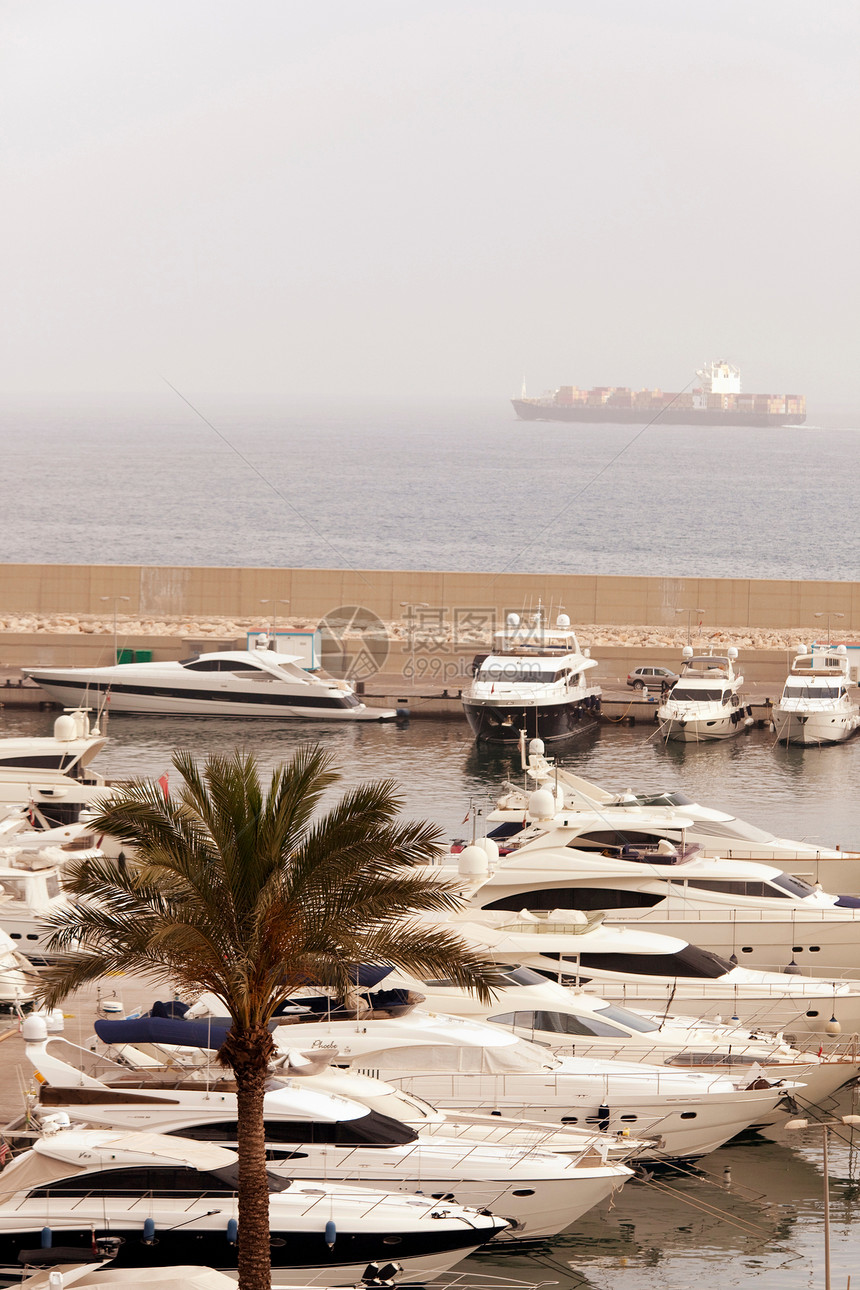 在黎巴嫩贝鲁特，一艘集装箱船在地中海航行时，豪华游艇停泊在码头墙壁内图片