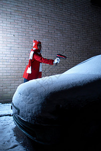 女孩用吹风机吹被雪覆盖的汽车图片