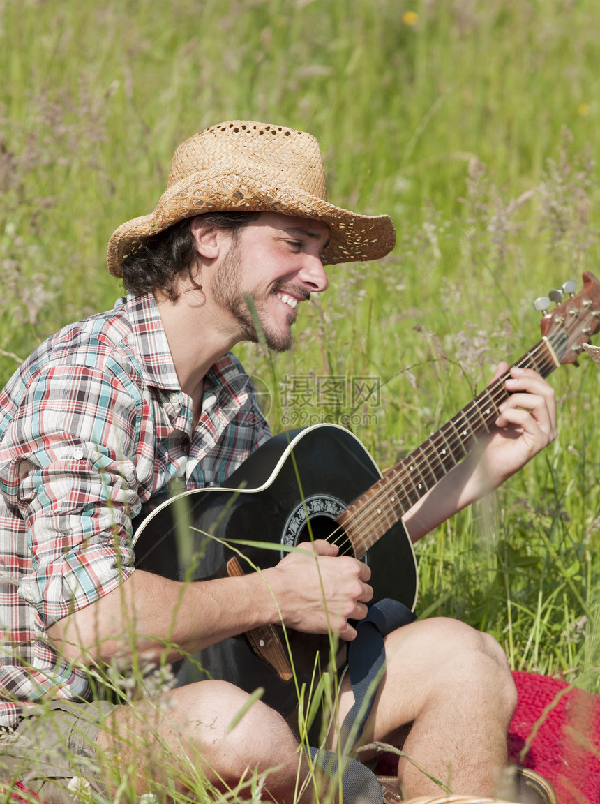 男性户外草地弹吉他图片