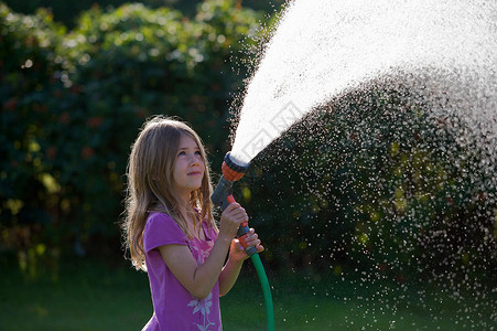 小女孩浇水小女孩用软管喷水背景