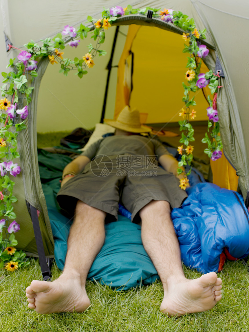 头戴帽子睡在帐篷里的男人图片