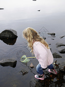 小女孩在湖中用网钓鱼图片