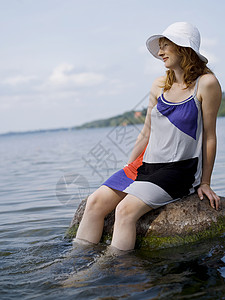 坐在水中岩石上的女人图片