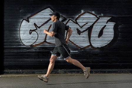 运动装男路过涂鸦的男跑步者背景
