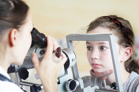 验光师检查女孩的眼睛视力背景图片